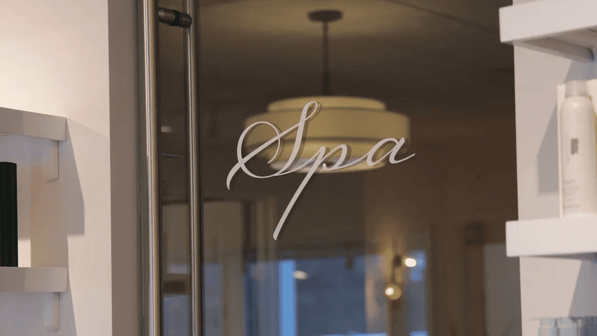 Glass door entrance to a modern spa, with shelves of skincare products.